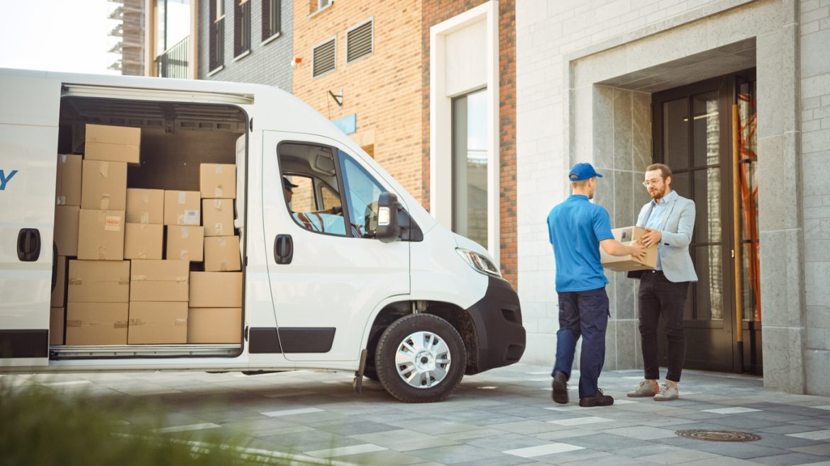 Delivery Man Gives Postal Package to a Business Customer, Who Signs Electronic Signature POD Device. In Stylish Modern Urban Office Area Courier Delivers Cardboard Box Parcel to a Man Delivering Excellence: Exploring London's Top Couriers